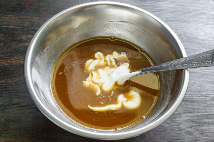 Adding broth and smetana to create a creamy sauce base. Pouring mushroom broth and smetana into the flour mixture to create the base for the mushroom sauce.