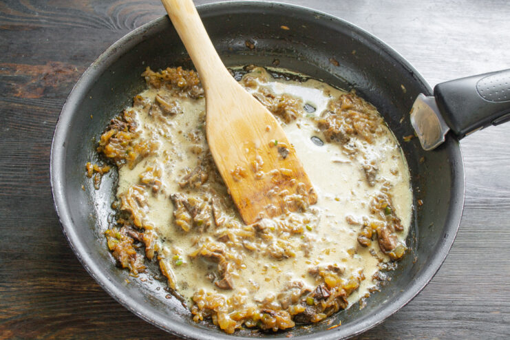 Adding chopped mushrooms to the sautéed onions. Adding finely chopped, rehydrated wild mushrooms to the pan of sautéed onions.
