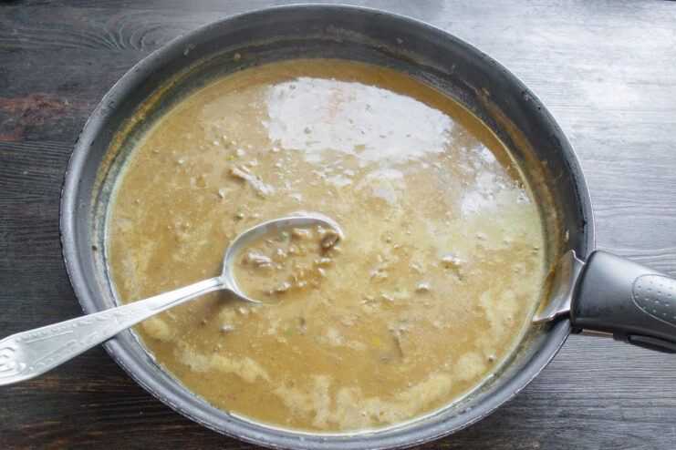Simmering the mushroom sauce to thicken and meld flavors. The creamy mushroom sauce simmering gently in a pan on the stove.