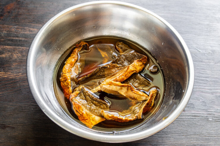 Rehydrating dried wild mushrooms for the sauce. Dried wild mushrooms soaking in a bowl of clear water to rehydrate them for the sauce.