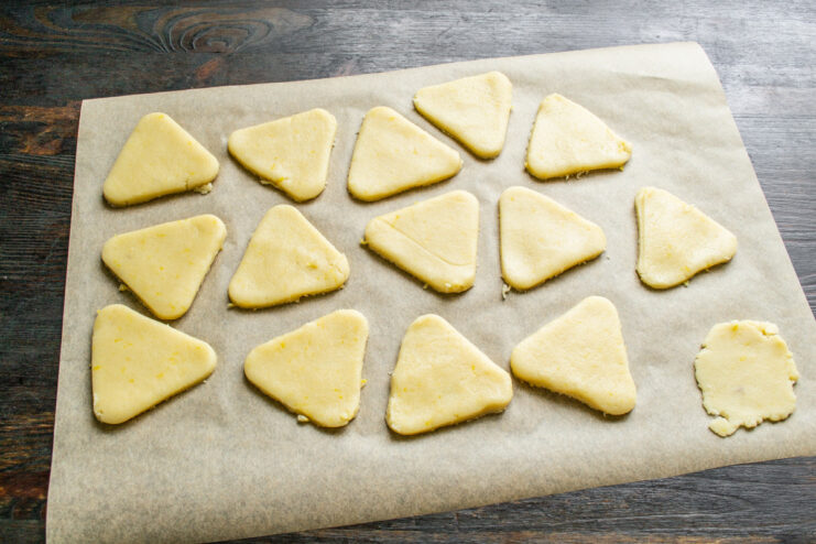 Raw, cut-out lemon cookies arranged on a baking sheet lined with parchment paper.