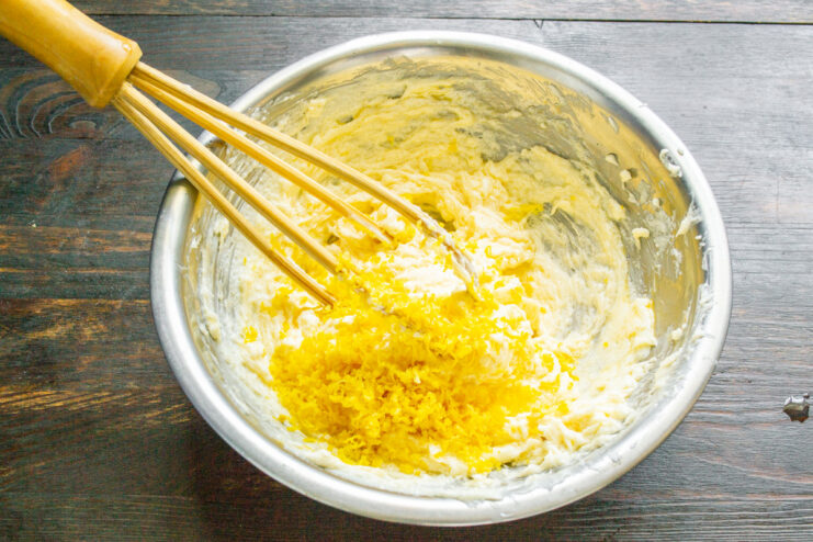 Adding freshly grated lemon zest to the cookie dough mixture.