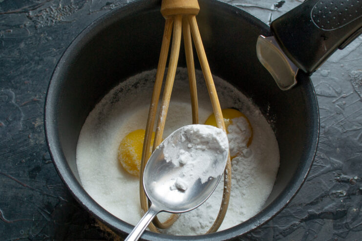 Adding Potato Starch to Thicken the Lemon Curd Adding a spoonful of potato starch to the saucepan with other ingredients.