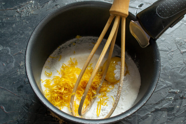 Infusing the Curd with Bright Flavor from Fresh Lemon Zest Adding freshly grated lemon zest to the mixture in the saucepan.