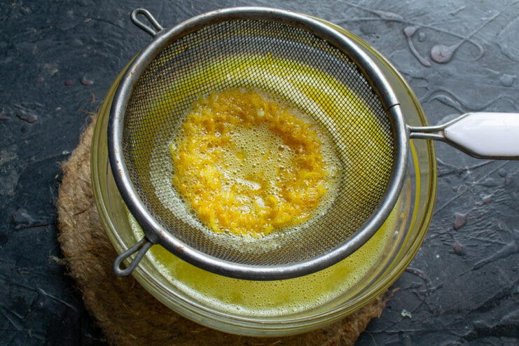 Straining the Cooked Curd for an Ultra-Smooth Finish Straining the thickened lemon curd through a sieve into a clean bowl.