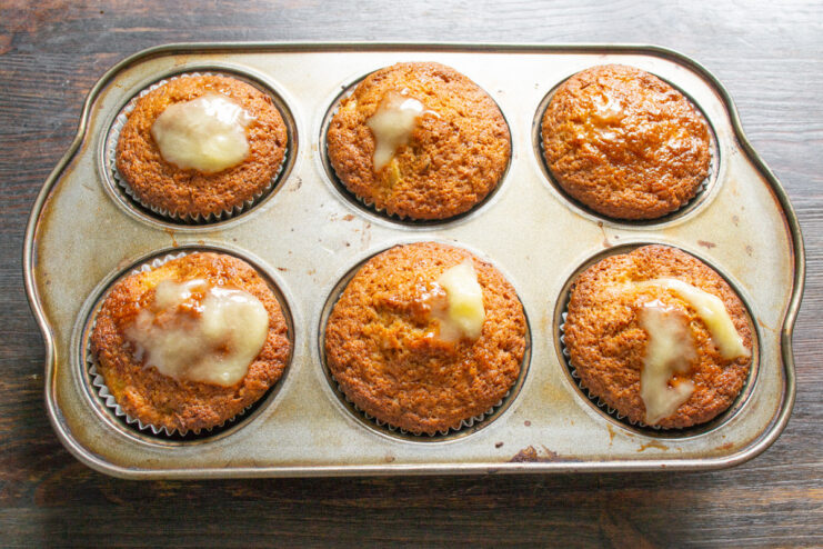 Step 9: Adding a touch of honey to the warm muffins for extra sweetness Drizzling honey over freshly baked, warm orange muffins.