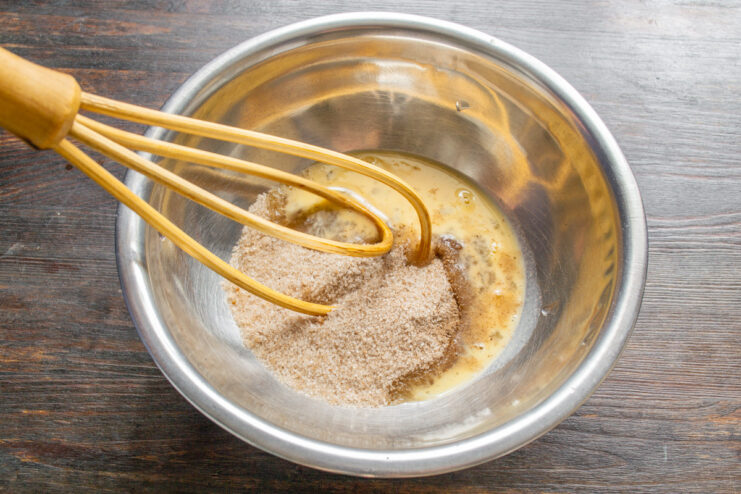 Step 1: Whisking the egg with sugar and cinnamon for the muffin batter A bowl with sugar, cinnamon, and an egg being mixed with a whisk.