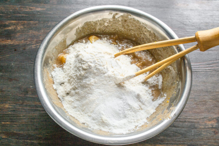 Step 5: Adding the dry ingredients - flour and baking powder Sifting flour and baking powder into the wet muffin ingredients.