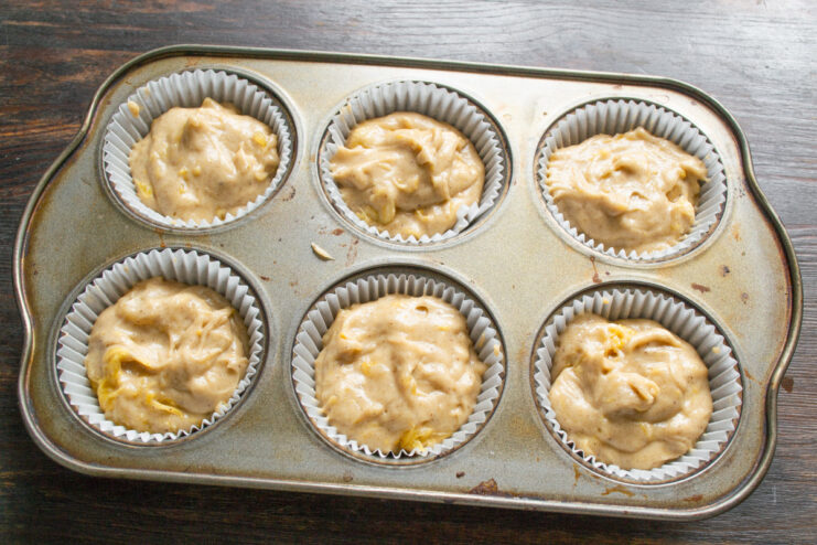 Step 7: Portioning the batter into muffin liners before baking Scooping muffin batter into paper liners in a muffin tin.