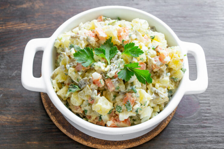 Serving the Perfect Potato Salad A serving of the best potato salad on a plate, beautifully garnished with a fresh parsley leaf.