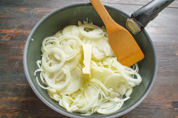 Slicing Onions Thinly for the Perfect Caramelization Close-up of hands slicing yellow onions into thin rings on a cutting board.
