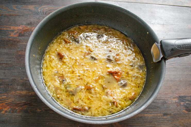 Creating the Savory Broth for the Onion Soup Pouring chicken broth into the skillet with onions and mushrooms.