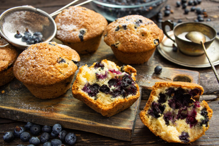 A plate of freshly baked blueberry muffins, dusted with powdered sugar.
