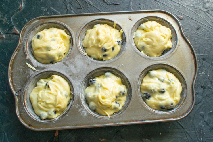 Filling the muffin cups with batter, ready for the oven Spoon the blueberry muffin batter into the prepared muffin tin.