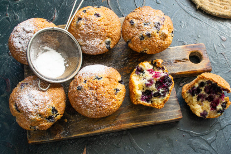 A final dusting of powdered sugar for a beautiful finish Dusting warm blueberry muffins with powdered sugar.