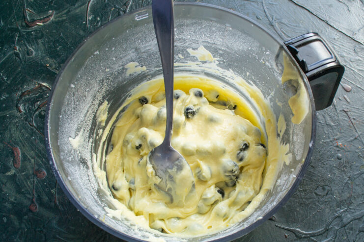Carefully mix the blueberries into the batter to avoid crushing them Gently folding fresh blueberries into the muffin batter with a spatula.