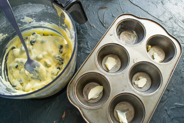 Properly greasing the muffin tin is key for easy removal after baking Greasing the cups of a muffin tin with softened butter.