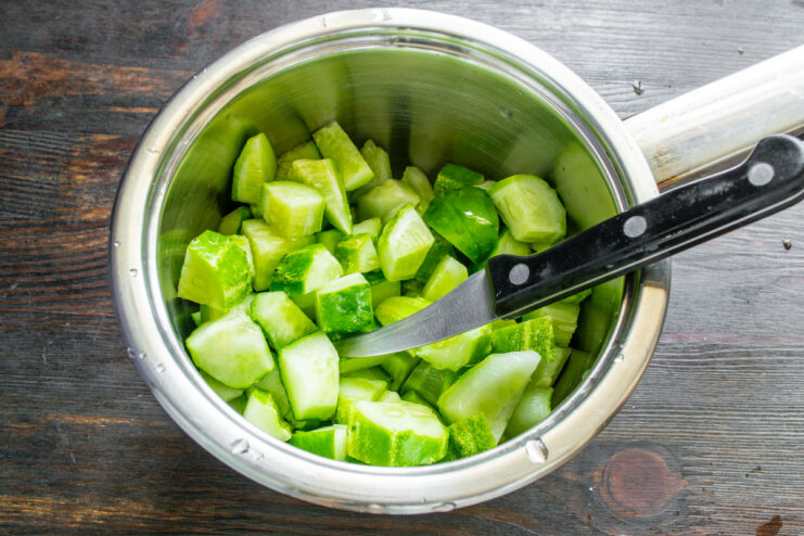 Step 1: Dicing Cucumbers for Pickling Fresh cucumbers cut into large cubes in a metal pot, ready for pickling.