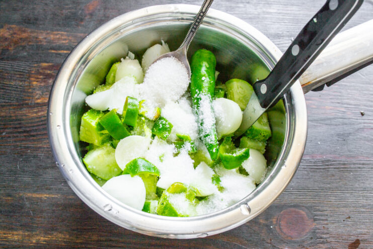 Seasoning the Vegetables with Salt and Sugar Salt and sugar being added to the pot with cucumbers, onions, and chili.