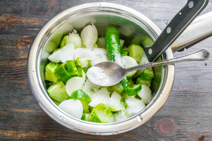 Adding Citric Acid for Preservation A spoonful of citric acid being added to the vegetable mixture in the pot.