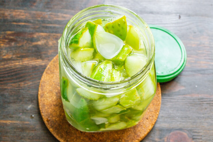 Packing the Hot Pickled Salad into a Jar Hot pickled cucumber salad being packed into a clean glass jar.