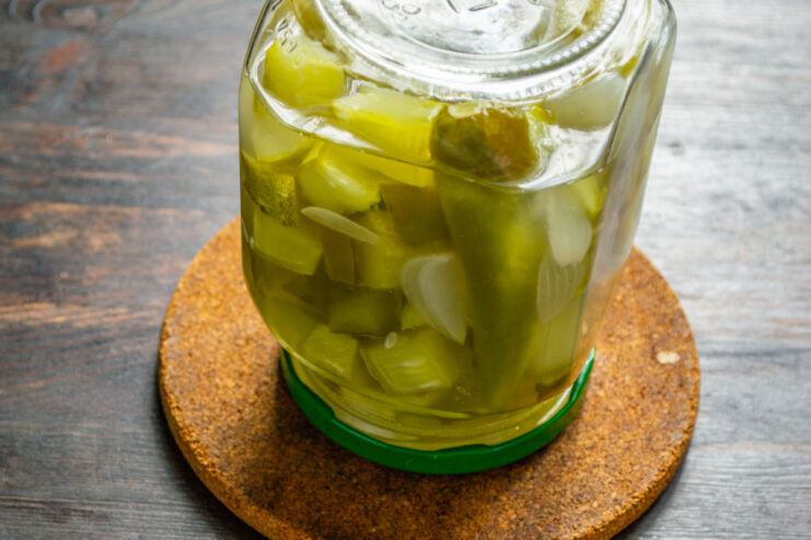 Final Step: Sealing and Cooling the Jar A sealed jar of pickled cucumbers turned upside down and wrapped in a towel to cool.