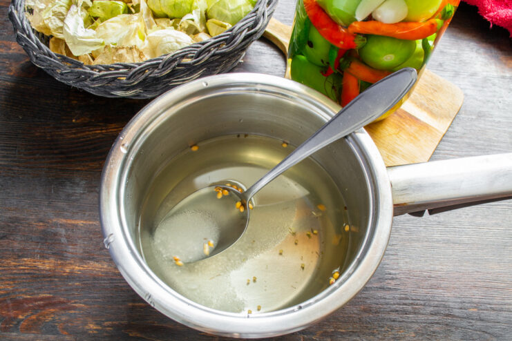 Making the sweet and sour pickling brine with aromatic spices. A saucepan with water, sugar, salt, and coriander seeds for the pickling brine.