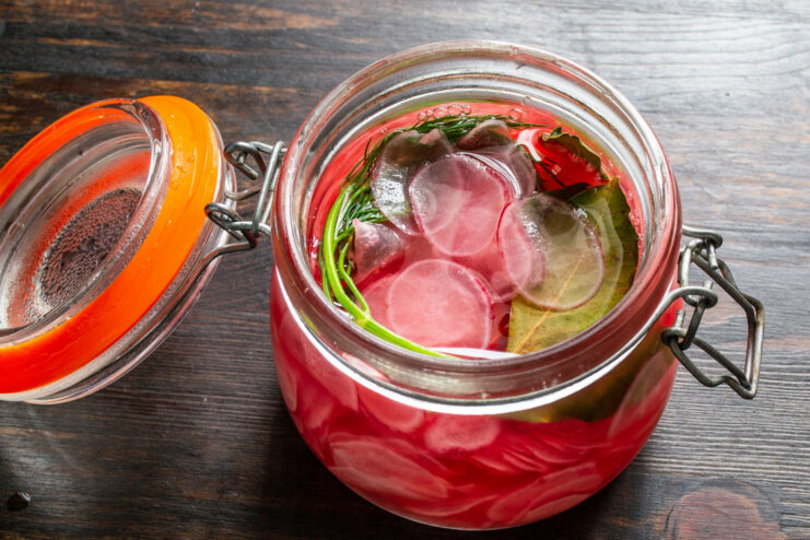The Delicious Result: Perfectly Marinated Pink Radishes A close-up of a jar filled with vibrant pink, thinly sliced marinated radishes.