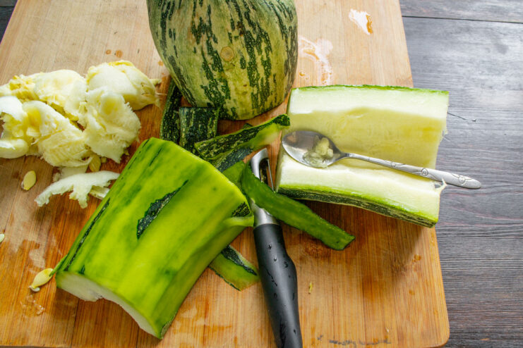 Preparing Zucchini: Scooping Out Seeds A hand using a spoon to scoop out the seeds from a halved zucchini.