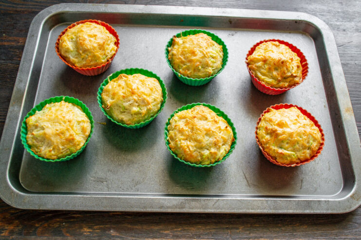 Baking Mini Casseroles in the Oven A baking sheet with silicone molds filled with zucchini casseroles baking in the oven.