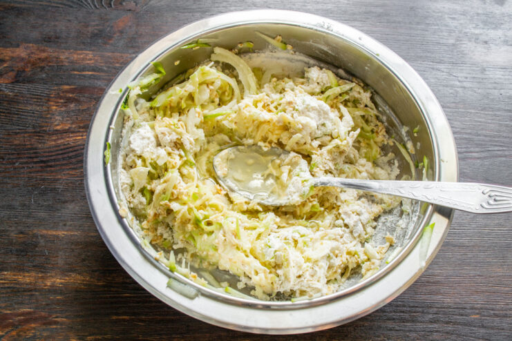 Adding Oil to the Batter Pouring vegetable oil into the bowl with the zucchini casserole mixture.