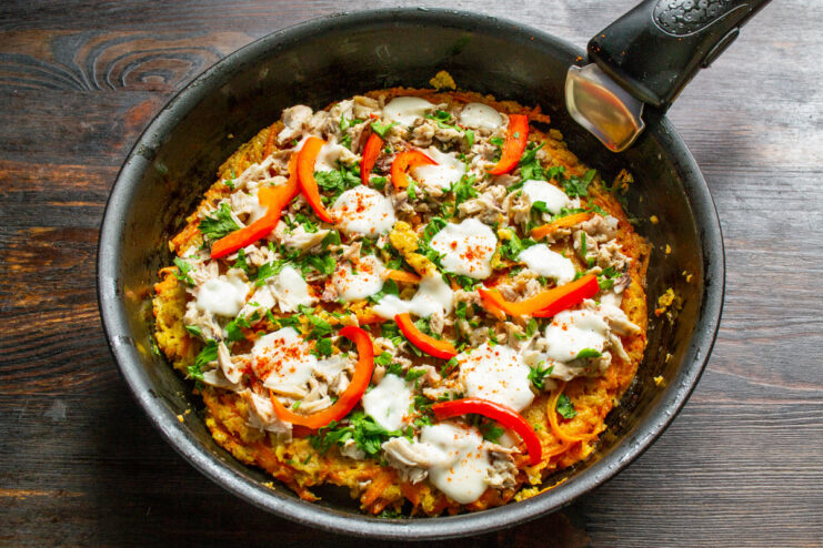 Serving the Hot and Ready Flourless Carrot Pizza The finished flourless carrot pizza in the skillet, with melted cheese and fresh toppings.