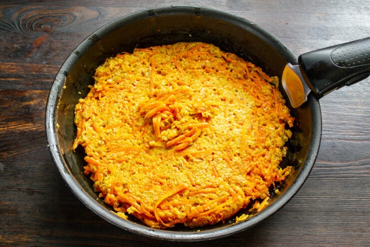 Flipping the Carrot Pizza Crust Like a Tortilla The carrot pizza crust being cooked in a skillet, ready to be flipped.