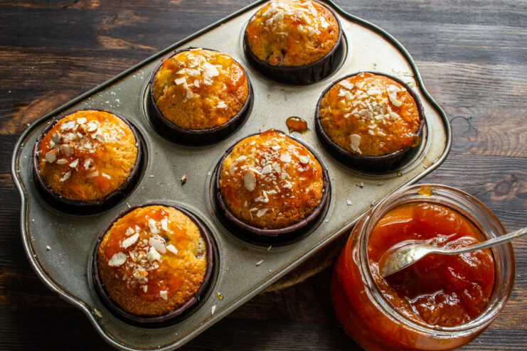 Decorating Carrot Muffins with Sliced Almonds Freshly glazed carrot and fig muffins being sprinkled with crunchy sliced almonds.