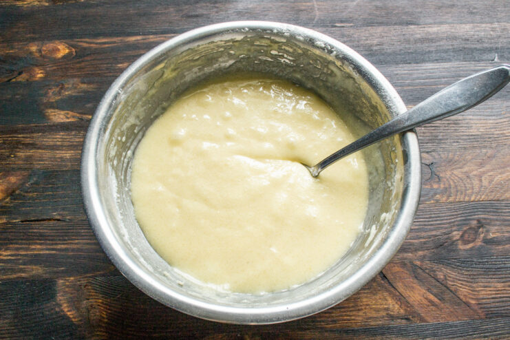 Mixing the Muffin Batter to a Smooth Consistency A smooth, light-colored muffin batter being mixed with a whisk in a glass bowl.