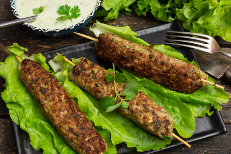 Plate of Egyptian-style meat kebabs with mint and cilantro, garnished with greens.