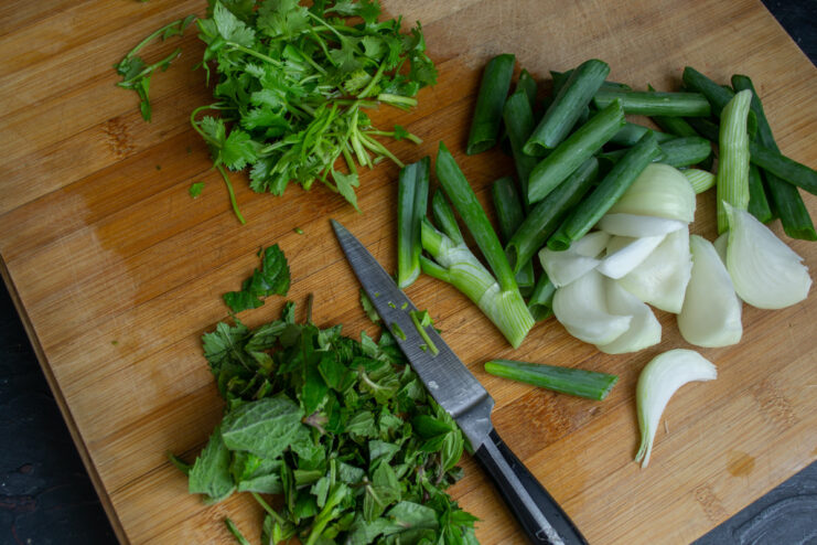 Fresh mint and cilantro being prepared for the kebab mixture. Fresh mint and cilantro on a cutting board.