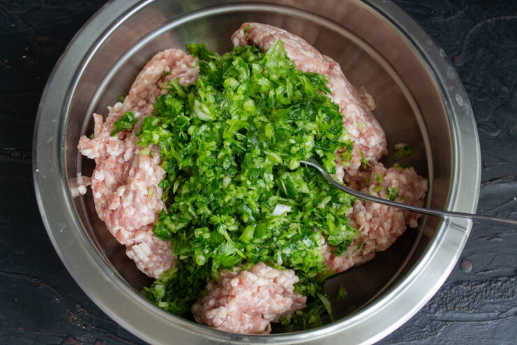 Blending fresh herbs into a paste for flavoring the meat kebabs. A blender jar filled with green herb paste made from mint and cilantro.