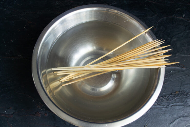 Tip: Soak wooden skewers in water to prevent them from burning during cooking. Wooden skewers soaking in a bowl of water.