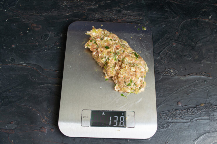 Portioning the kebab mixture for even cooking. The ground meat mixture divided into six equal portions on a cutting board.