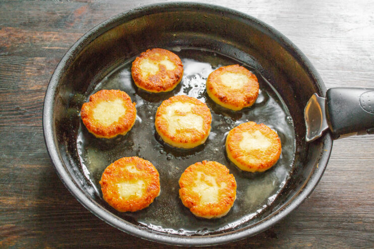 Finishing the Syrniki - Frying until golden brown and draining excess oil. Golden-brown fried syrniki resting on a paper towel to absorb excess oil.