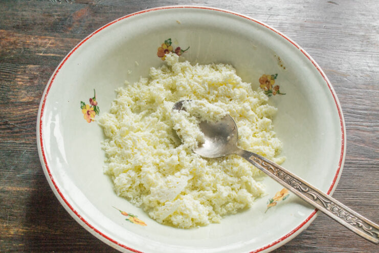 Sifting Tvorog for Smooth Syrniki Dough - The key to a perfect texture. Tvorog (farmer's cheese) being pressed through a fine-mesh sieve into a white bowl.