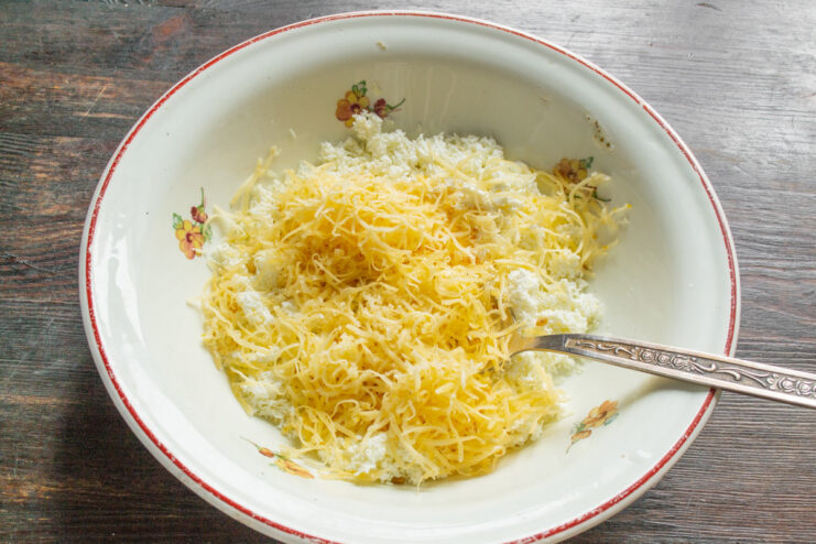 Grating Cheese for Savory Syrniki - Adding extra flavor and texture. A block of semi-hard cheese being grated on a box grater.