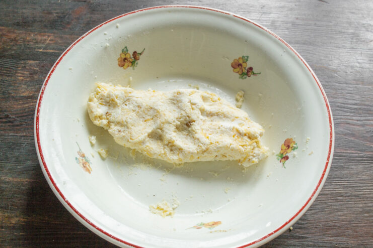 Mixing the Syrniki Dough - Aim for a firm, non-sticky consistency. A thick, well-mixed dough for savory syrniki in a white bowl with a spoon.