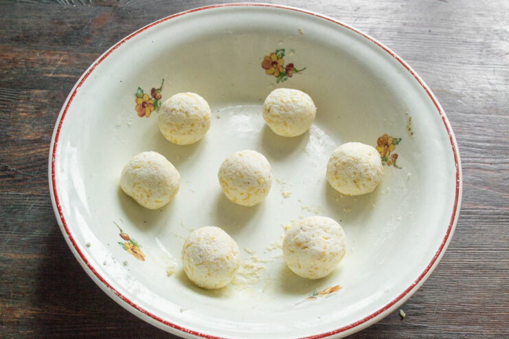Shaping the Syrniki - Rolling the dough into smooth balls. Hands rolling a piece of syrniki dough into a perfect ball.