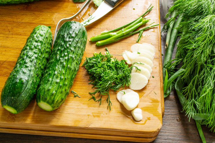 Using both dill fronds and stems adds a deep, aromatic flavor. Fresh dill being chopped on a cutting board, with stems set aside.