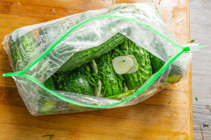 The 'bag method' is a clean and simple way to make quick pickles. Cucumbers, garlic, and dill being placed into a large ziplock bag.