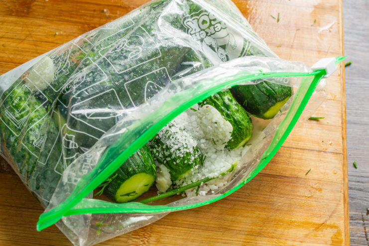 Coarse sea salt is ideal as it helps draw out moisture and acts as an abrasive. Coarse sea salt being poured from a hand into the ziplock bag with cucumbers.