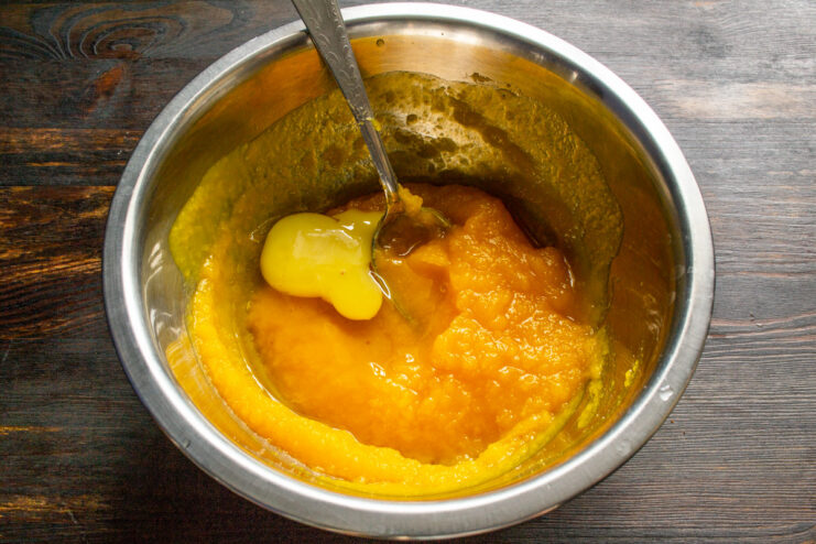 Adding Eggs to the Pumpkin Batter. This step helps bind the pancakes and make them fluffy. Two eggs being cracked into a bowl containing smooth pumpkin purée.