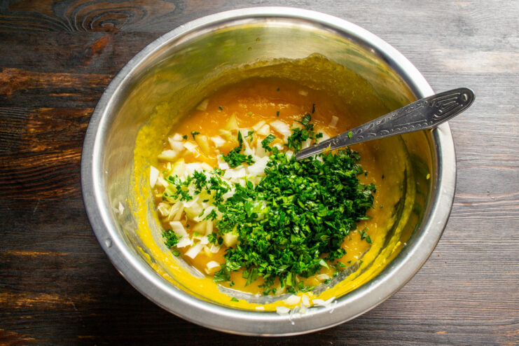 Adding Fresh Parsley for a Burst of Flavor. Fresh herbs elevate these savory pancakes. A hand adding a pile of finely chopped fresh parsley to the pumpkin pancake batter.